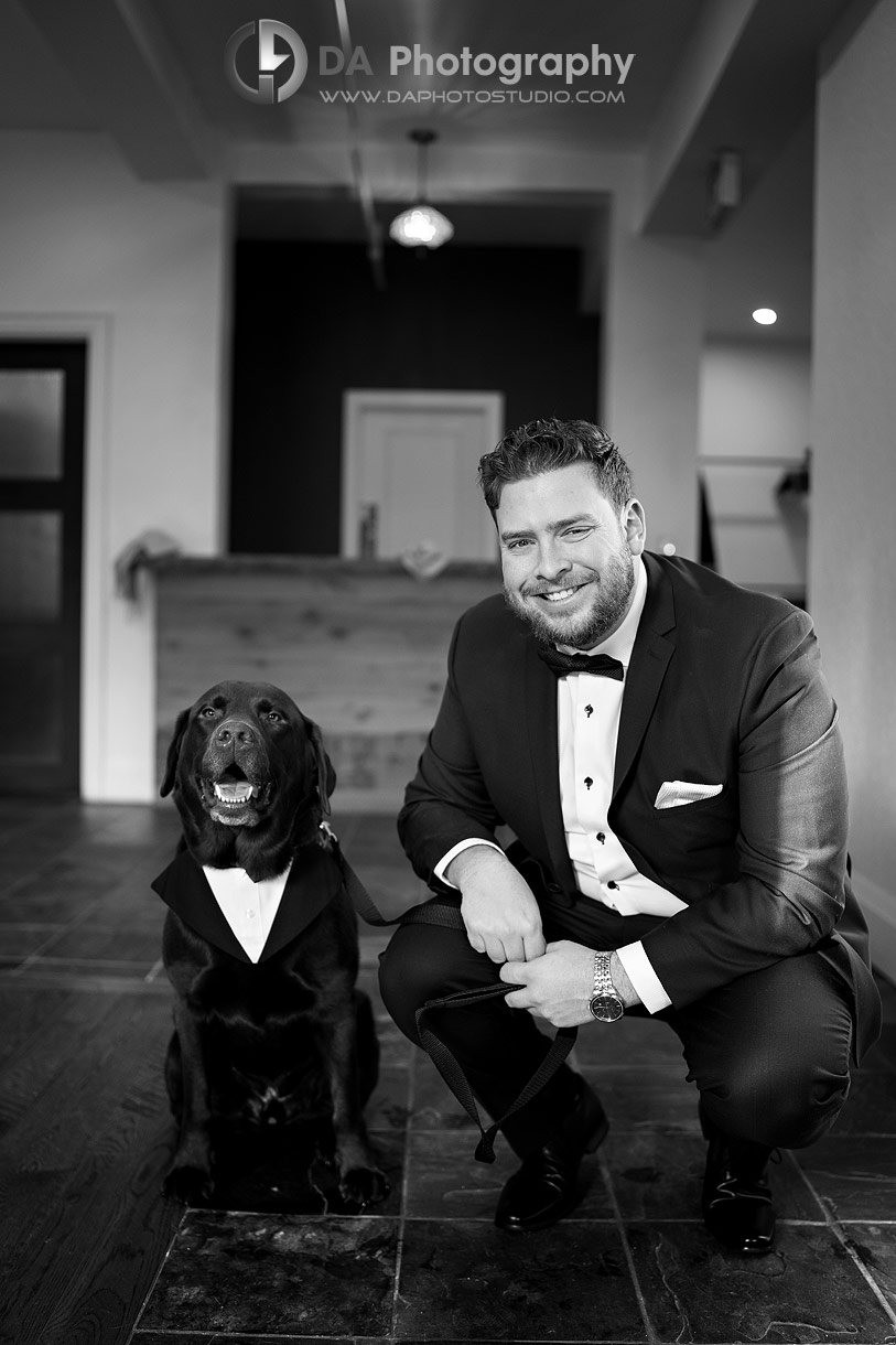 Photo of a groom with his dog, both with a bow ties