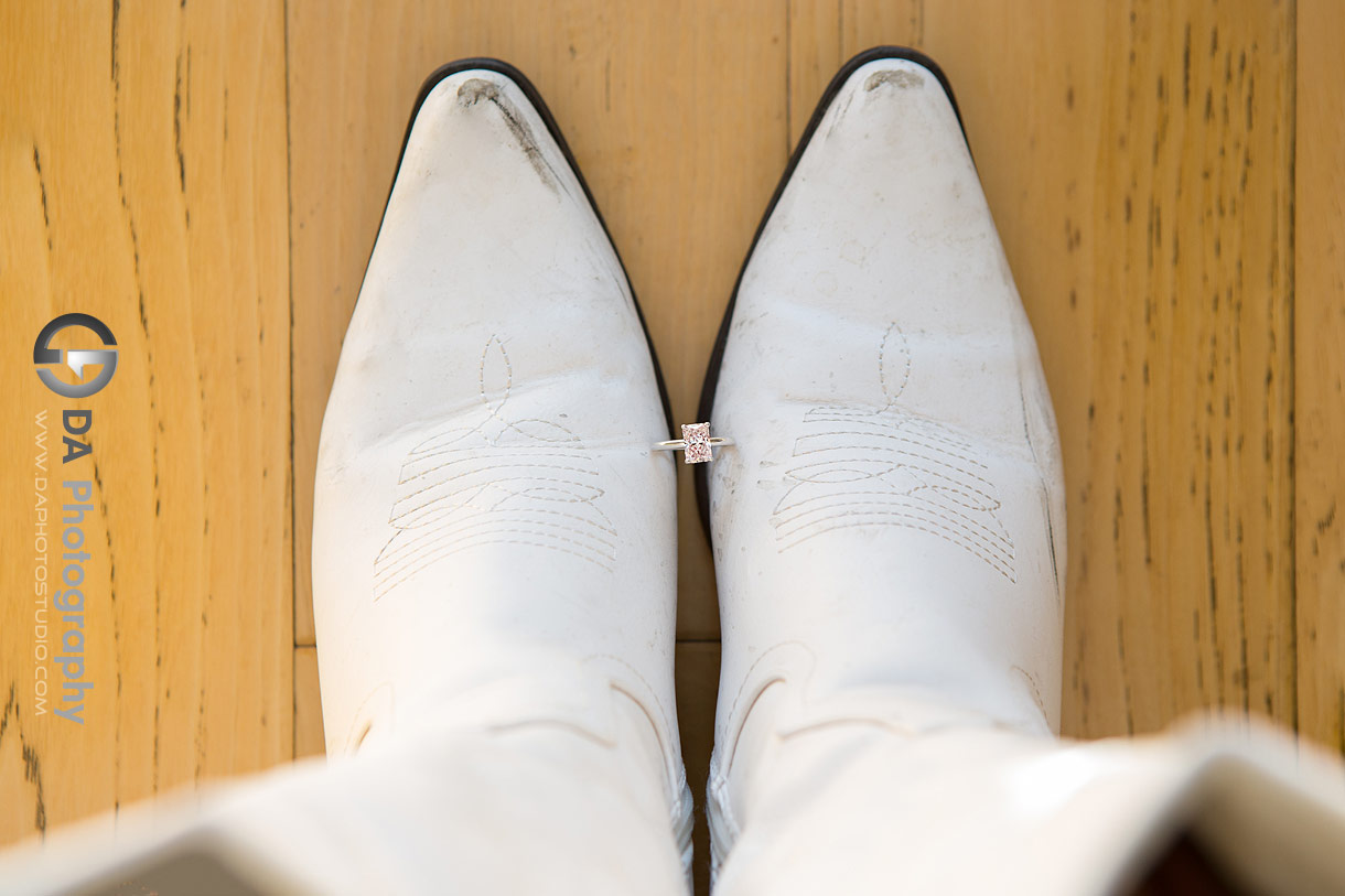 Photo of white bride's wedding boots with the engagement ring in between