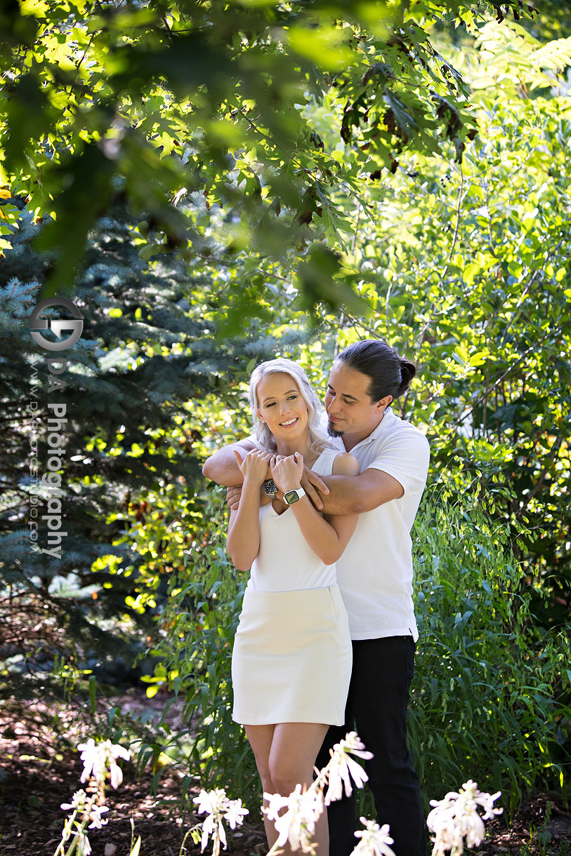 Engagement photo of a couple surrounded by summer greenery