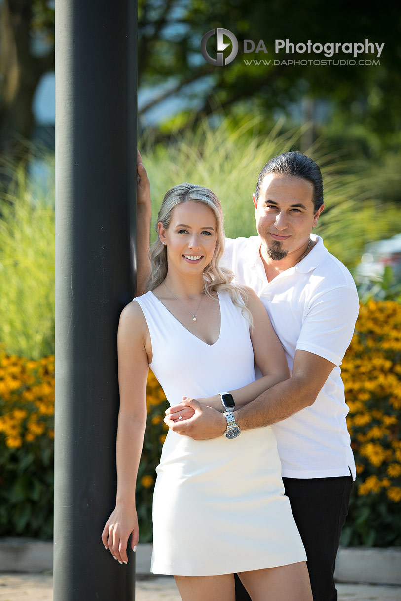 Engaged couple standing between vibrant garden flowers at Westwood Park in Oakville