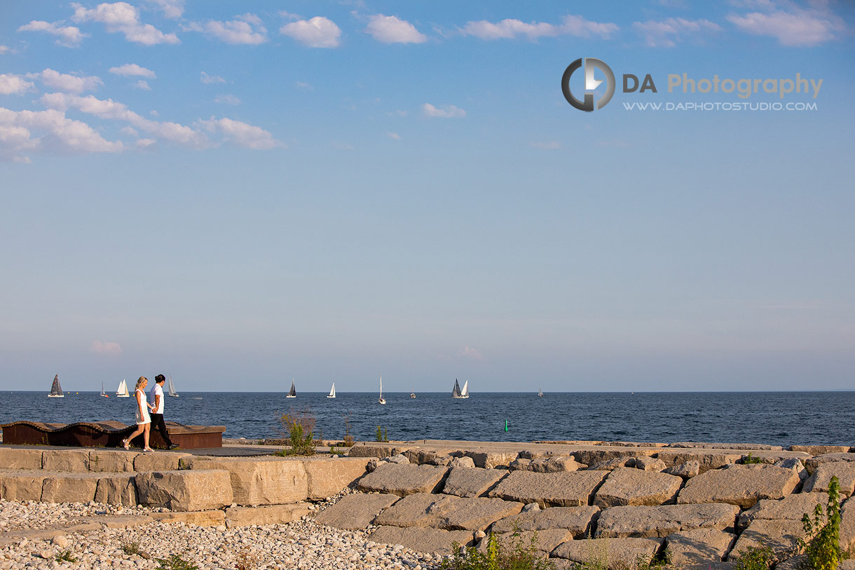 Couple walking along the waterfront path at Tannery Park with the Oakville Harbour behind them