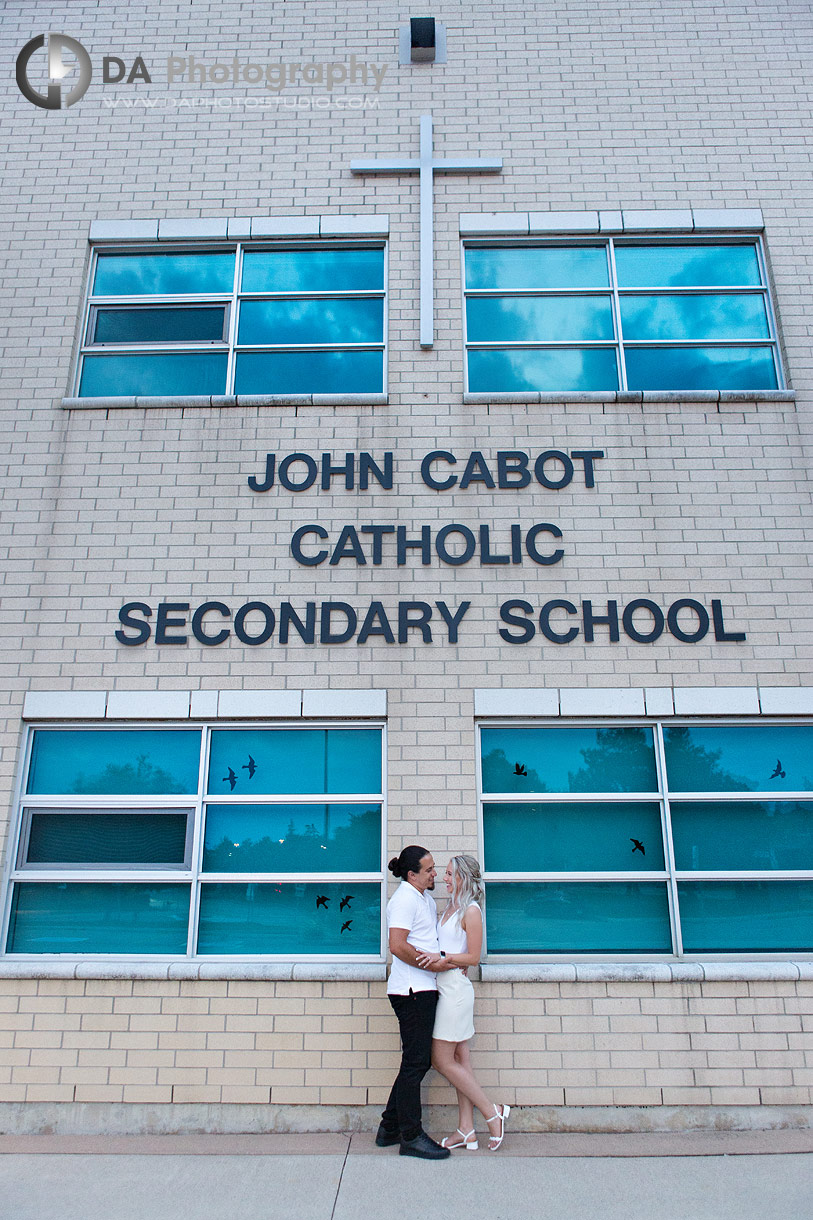 Couple standing in front of John Cabot Catholic Secondary School sign during twilight