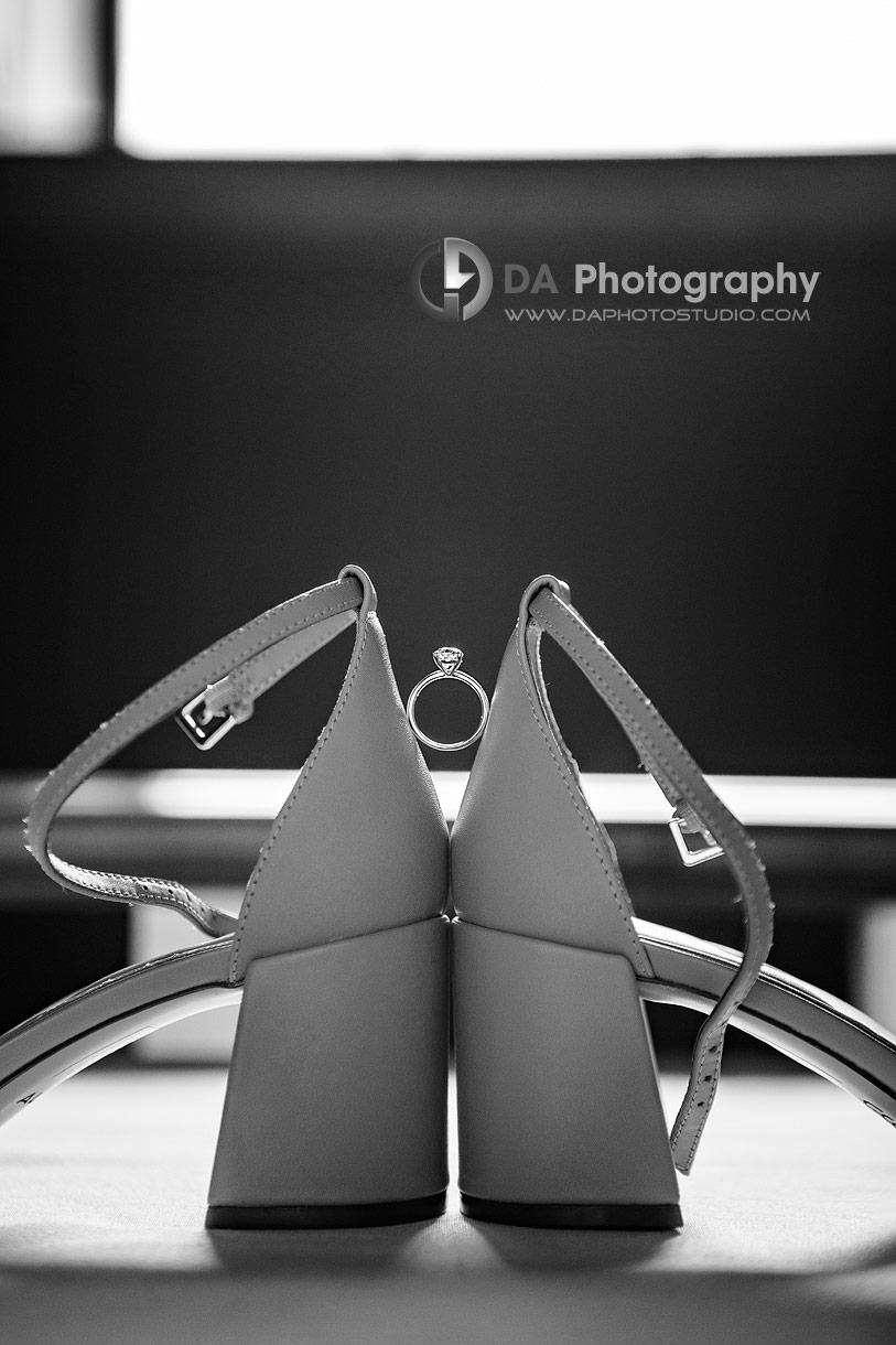 Photo of a Engagement ring between the backs of a bride shoes 