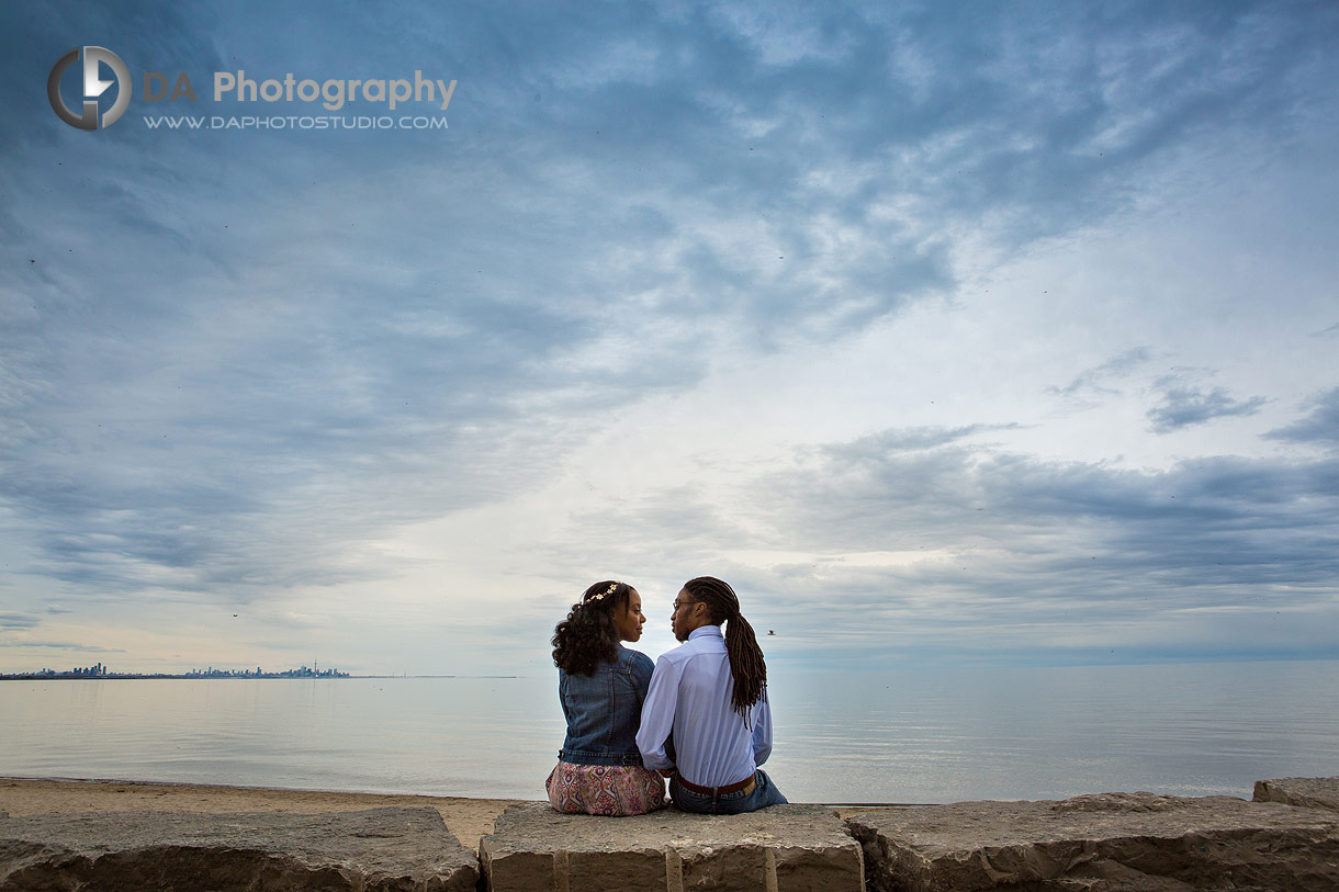Photo of a couple by the lake with dramatic clouds during sunset
