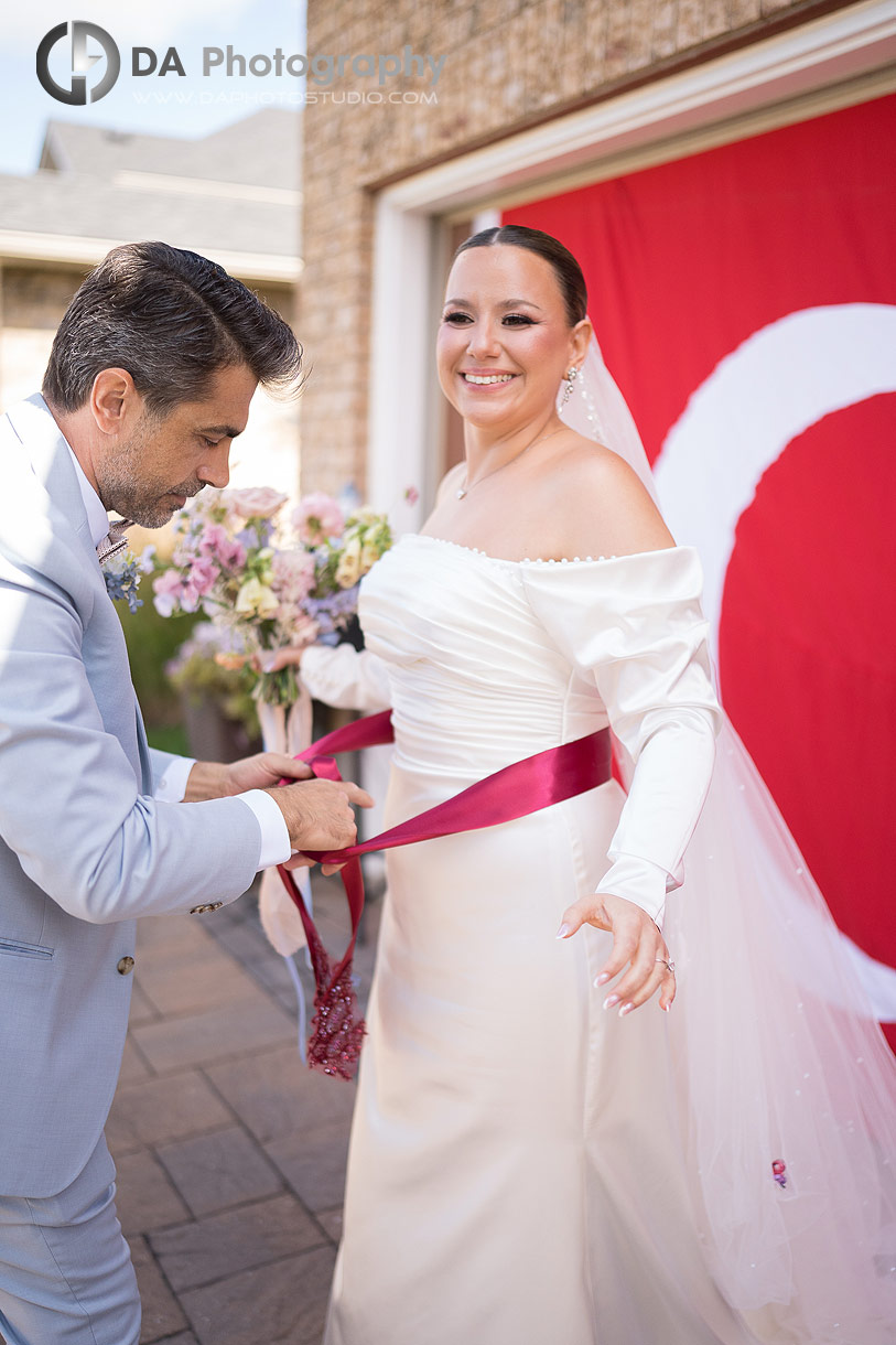 Godfather tying a ribbon on Bride's waist during Turkish Wedding Ceremony
