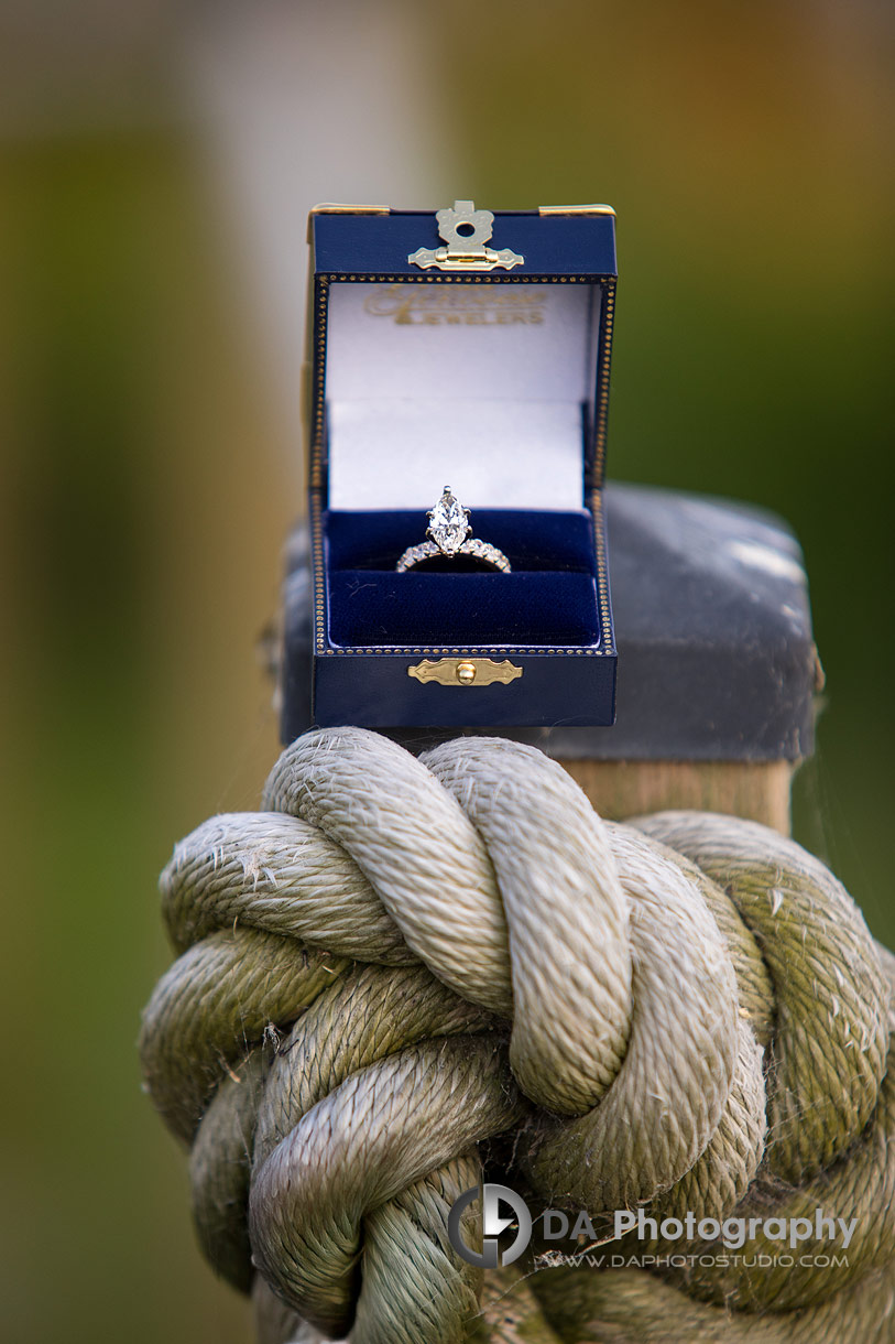 Close up photo of an engagement ring in a box laying on a large rope knot 