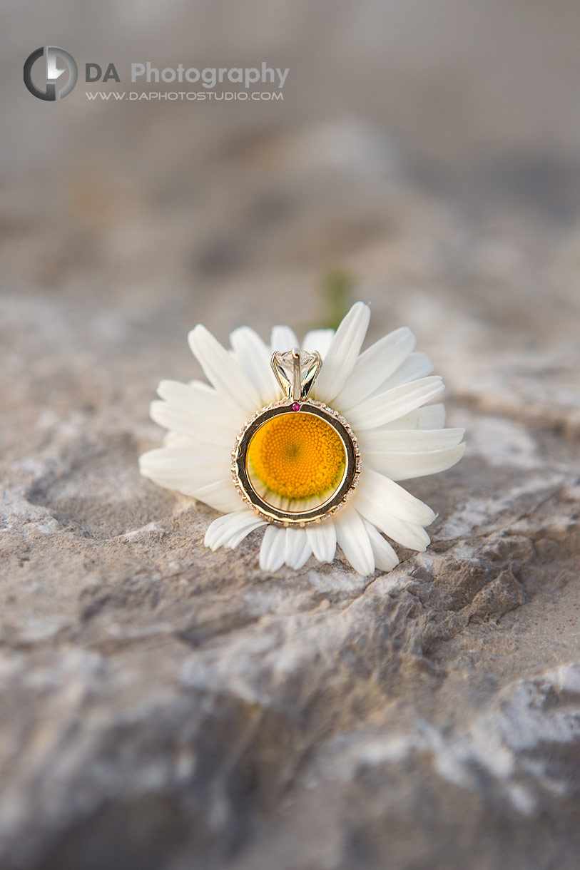 Close up photo of an Engagement ring next to flower